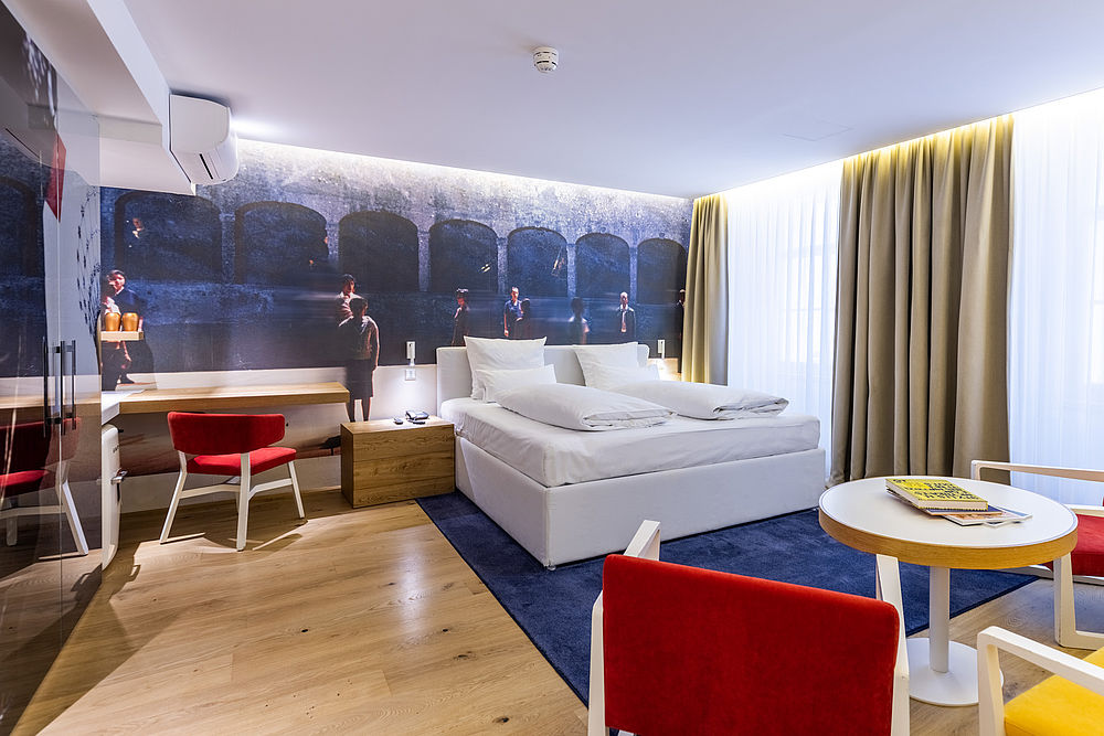 Ein weitläufiges Hotelzimmer mit einer blauen Wandtapete und einem blütenweisen Bett