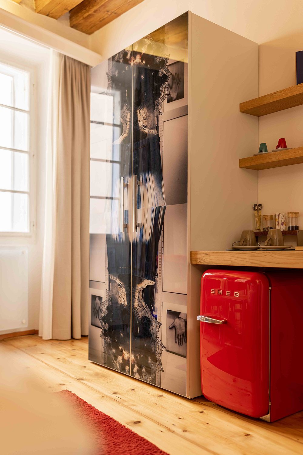 Ein glänzender Kleiderschrank neben der schicken Kücheninsel inklusive eines roten Kühlschranks