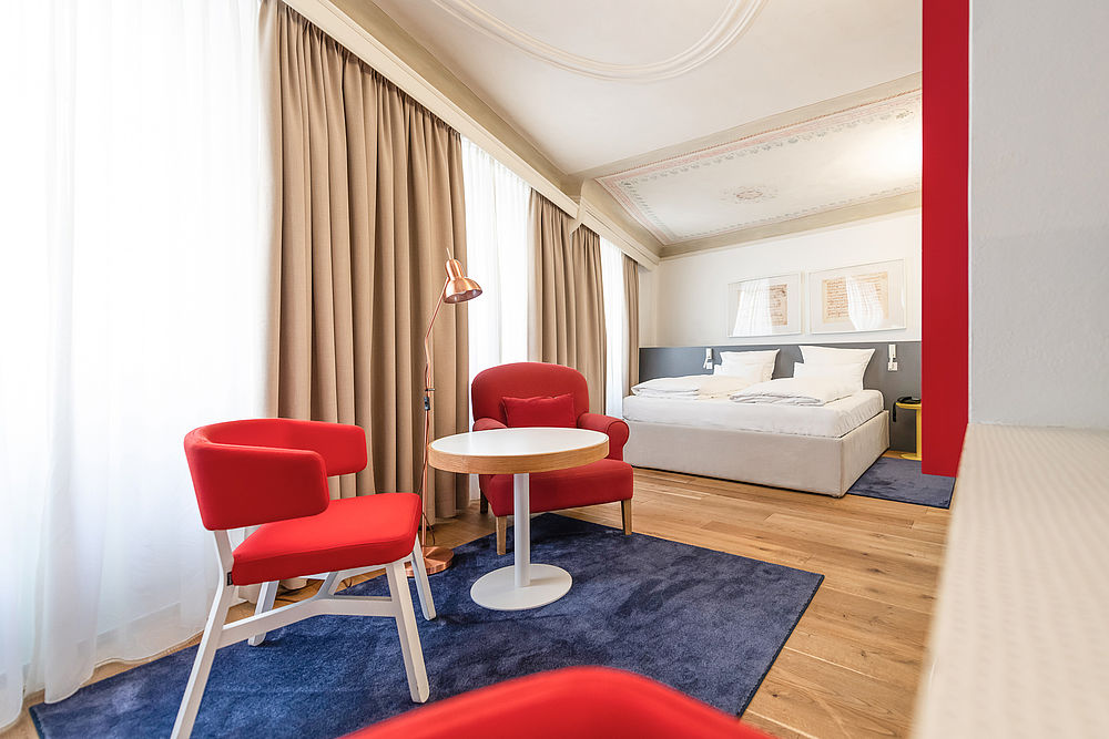 Geräumiges Schlafzimmer der Juniorsuite mit blauem Teppich und Doppelbett im romantischen Hotel Salzburg