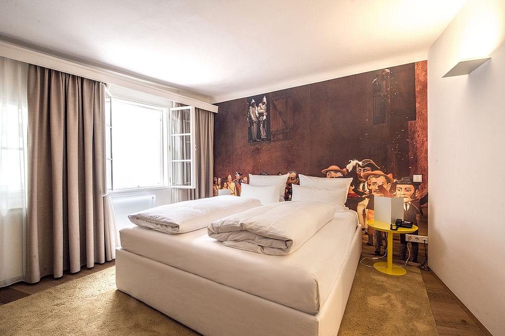 Schlafzimmer der Juniorsuite mit weißem Boxspringbett und Fototapete im romantischen Hotel Salzburg