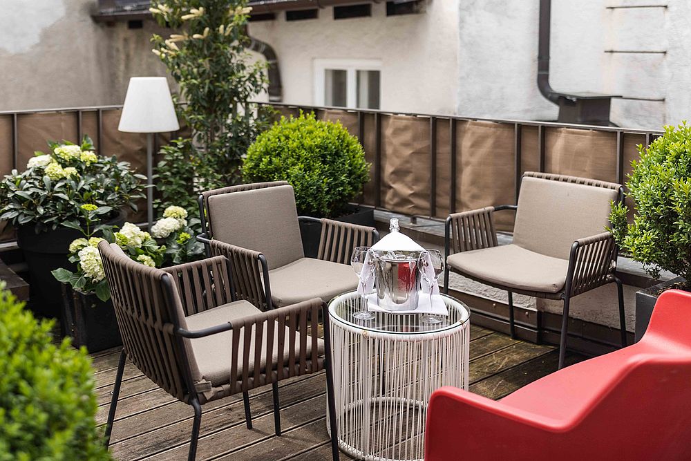 Die bepflanzte Terrasse des Hotel Goldgasse mit Sitzgelegenheiten und Wein