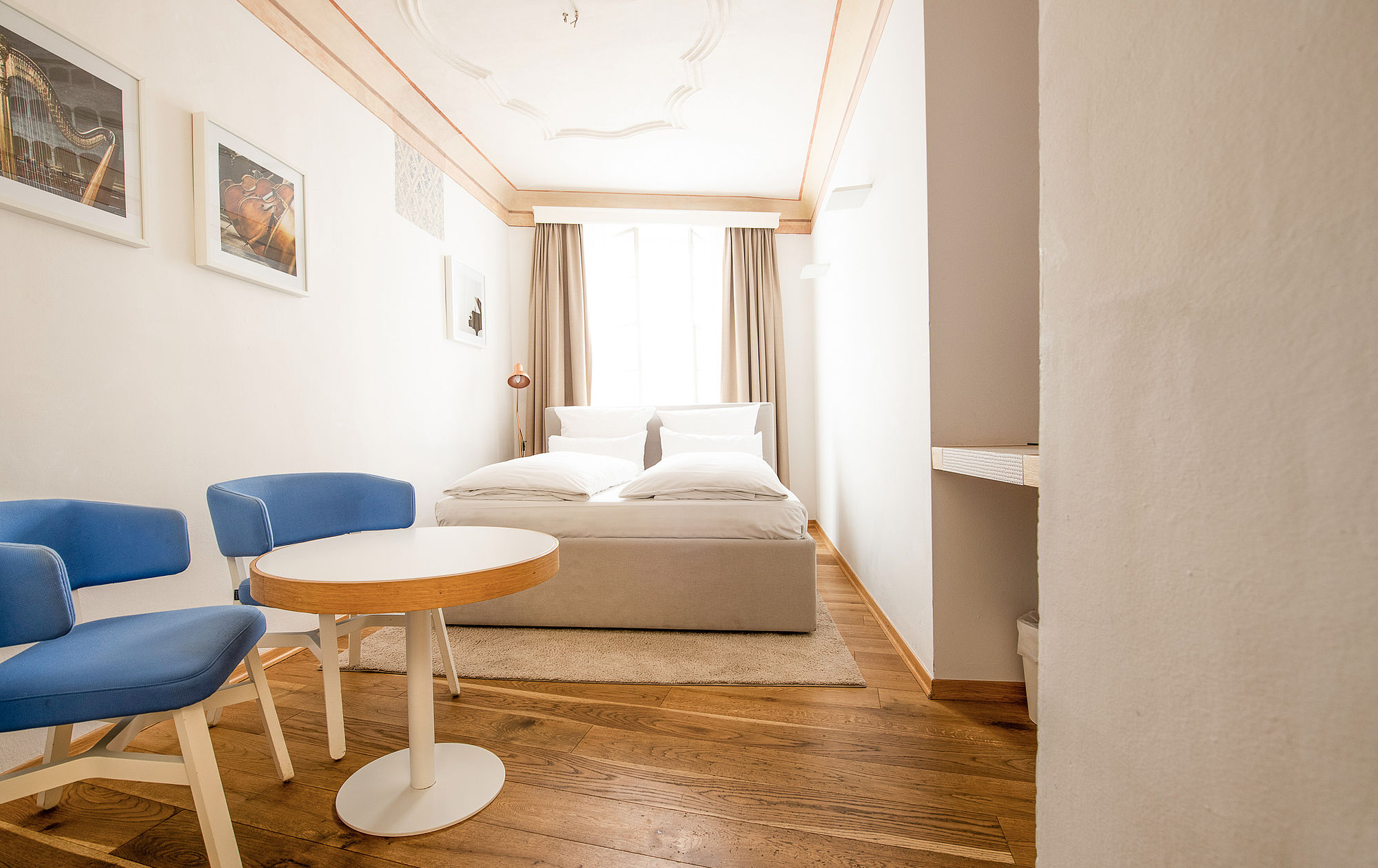 Doppelzimmer mit Bett in der Ecke und Stühlen mit Tischchen im Vordergrund im Boutique Hotel Salzburg
