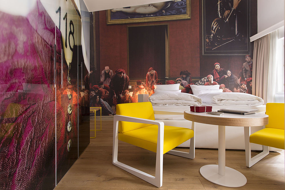 Stylisches Schlafzimmer mit gelben Stühlen und Doppelbett im Hintergrund im romantischen Hotel Salzburg