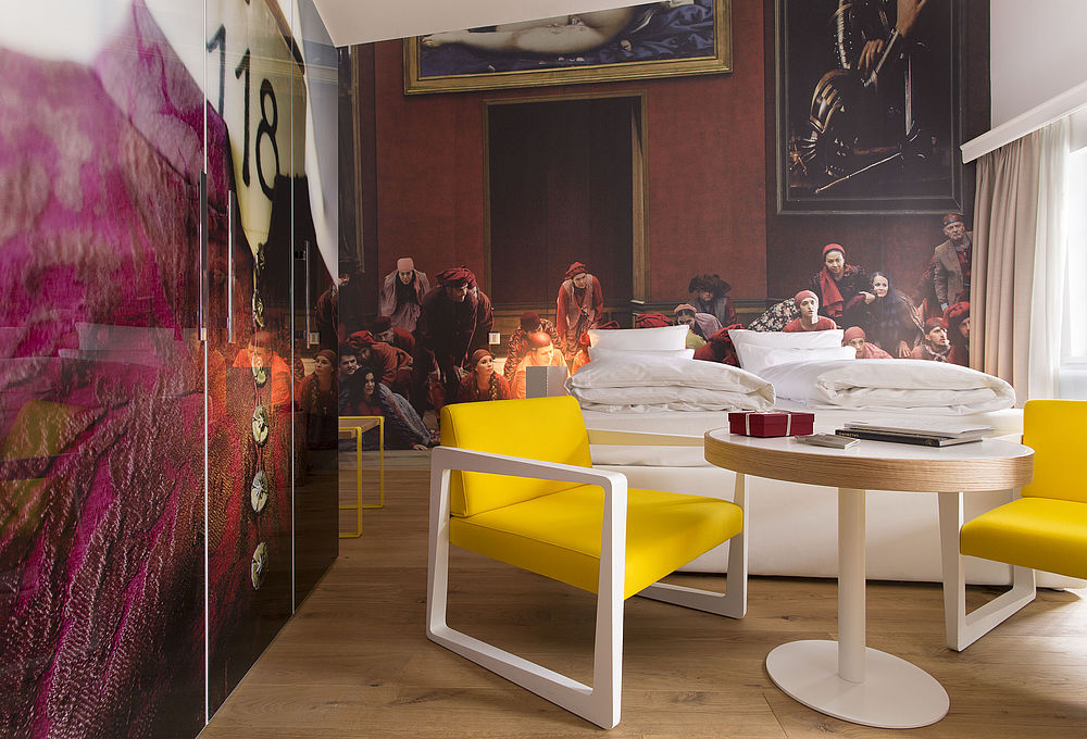 Stylisches Schlafzimmer mit gelben Stühlen und Doppelbett im Hintergrund im romantischen Hotel Salzburg