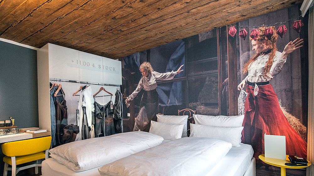 Doppelbett umgeben von stylischen Kleiderschrank und Fototapete im Boutique Hotel Salzburg