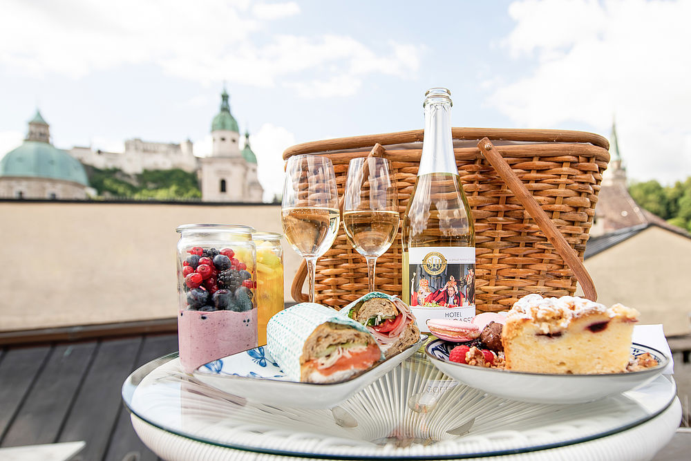 Ein Picknickkorb mit Kuchen, Baguette, Jogurt und einer Weißweinflasche des Hotel Goldgasse
