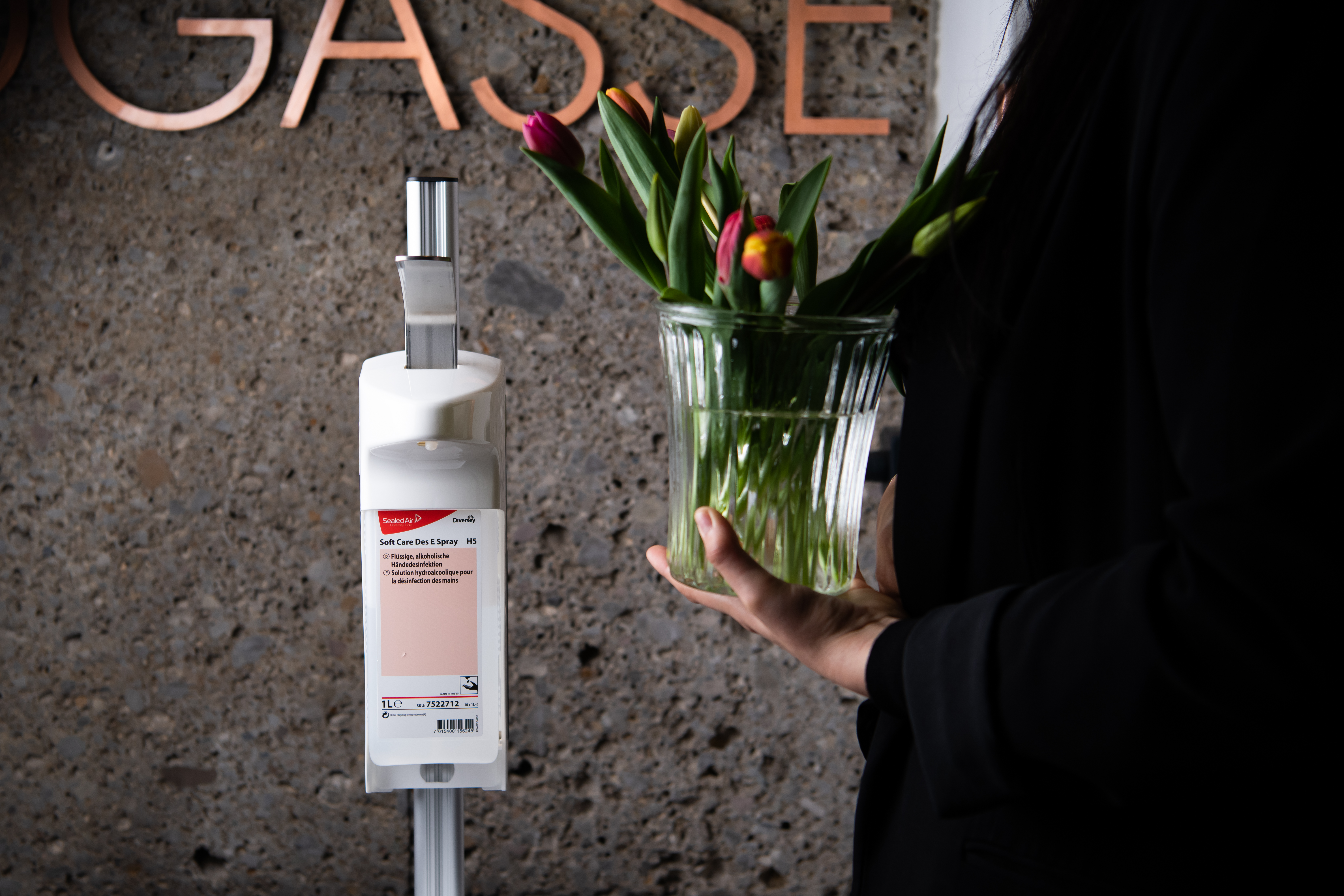 Angestellte des Boutique Hotel Salzburg läuft an einem Desinfektionsspender vorbei